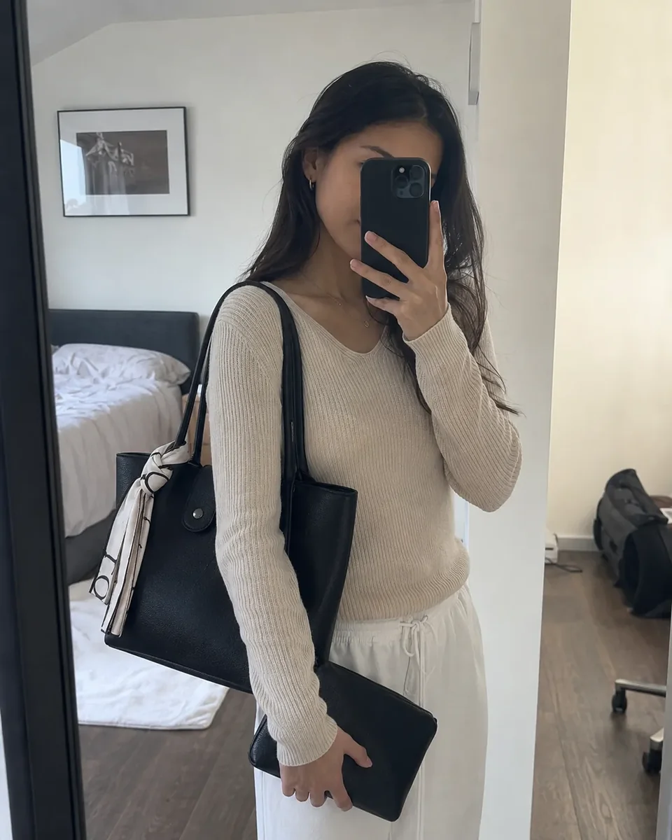 The Everyday Tote and Mini Essentials Pouch in Noir, carried over the shoulder